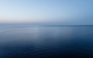 Ruhige dunkelblaue Meer­esfläche mit leichter Wellenstruktur, heller Horizont im oberen Bilddrittel